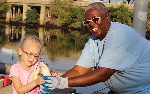 A young angler checks out her catch with a Fish Fest volunteer. Credit: Philadelphia Water